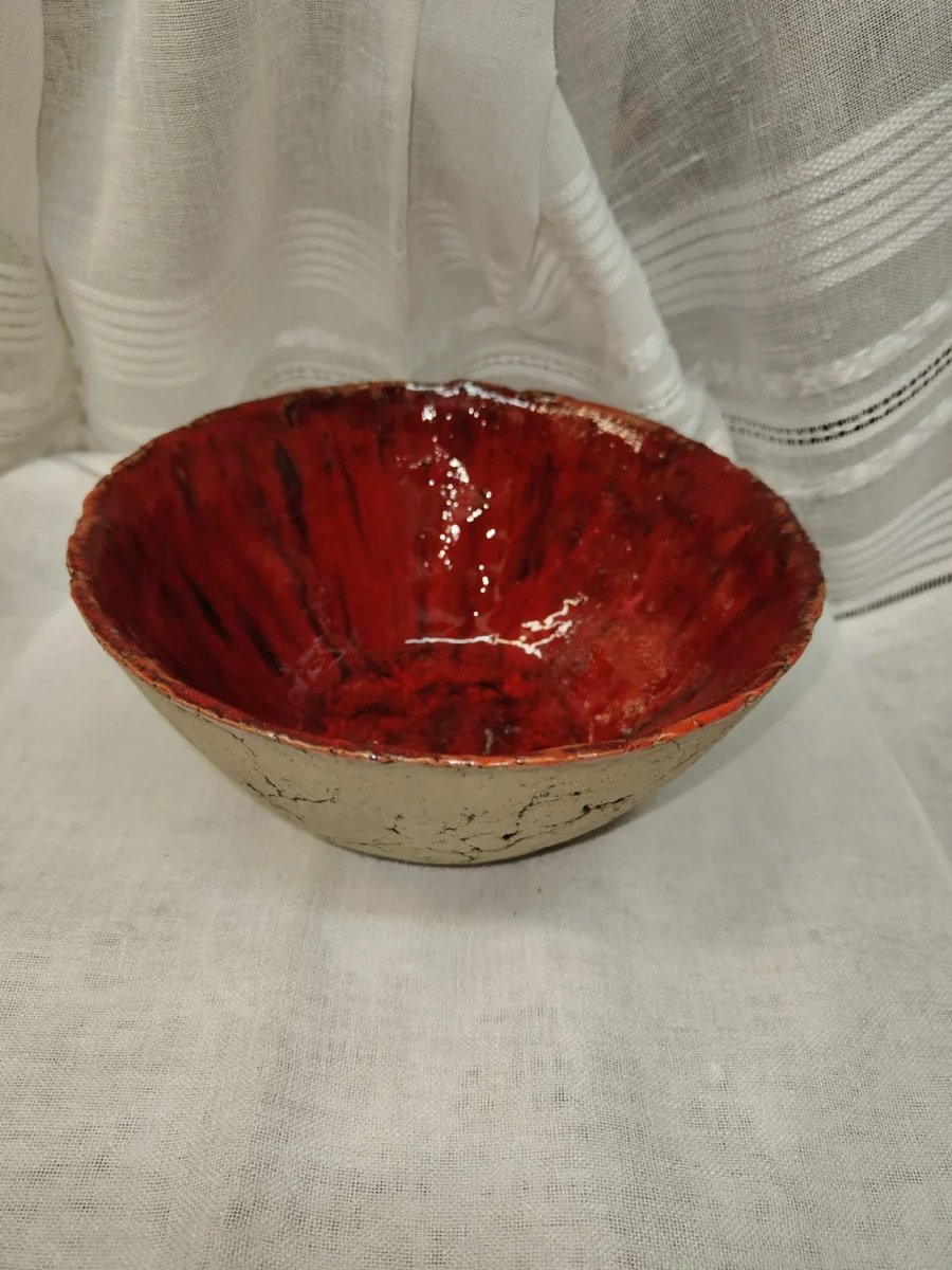 Ceramiczna misa z czerwonym, żłobionym wnętrzem i jasną powierzchnią zewnętrzną.
