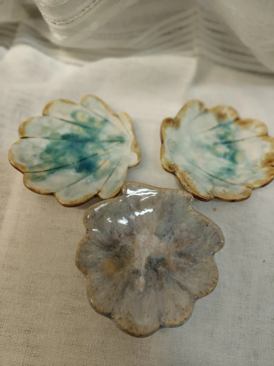 Trzy ceramiczne formy w kształcie kwiatów, w bieli, turkusie i szarości.