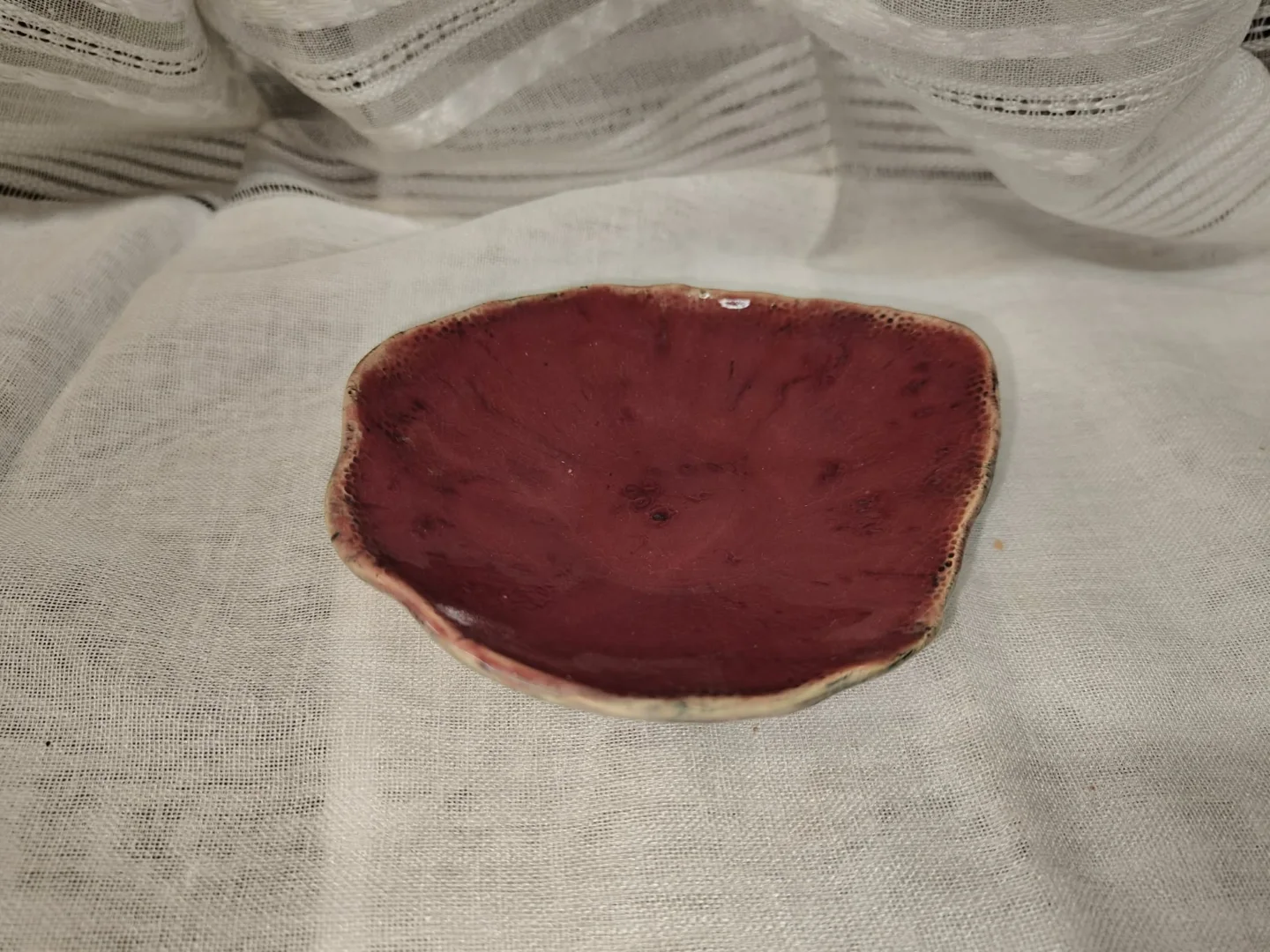 Nieregularna ceramiczna miseczka z malinowym wnętrzem i jasnobrązowym brzegiem.