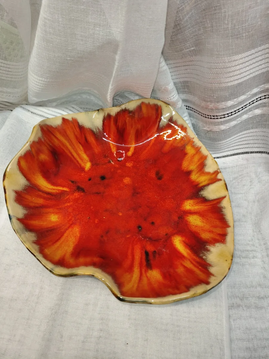 Ceramiczna patera w kształcie kwiatu z czerwono-pomarańczowym środkiem i jasnym brzegiem.