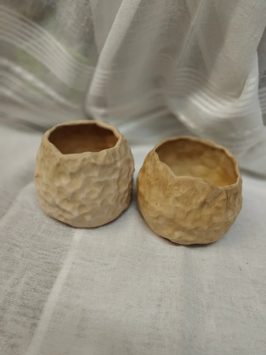 Niewielkie naczynia ceramiczne w piaskowych i miodowych odcieniach z fakturowaną powierzchnią.