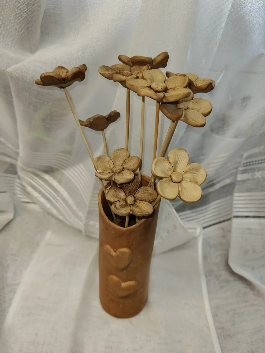 Bukiet beżowych ceramicznych kwiatów o zaokrąglonych płatkach na cienkich łodygach.