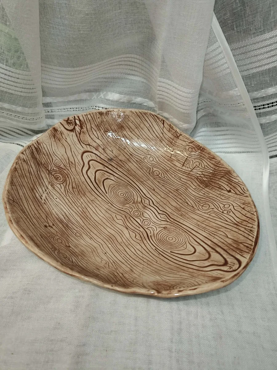 Jasna ceramiczna patera z brązowym rysunkiem przypominającym słoje drewna.