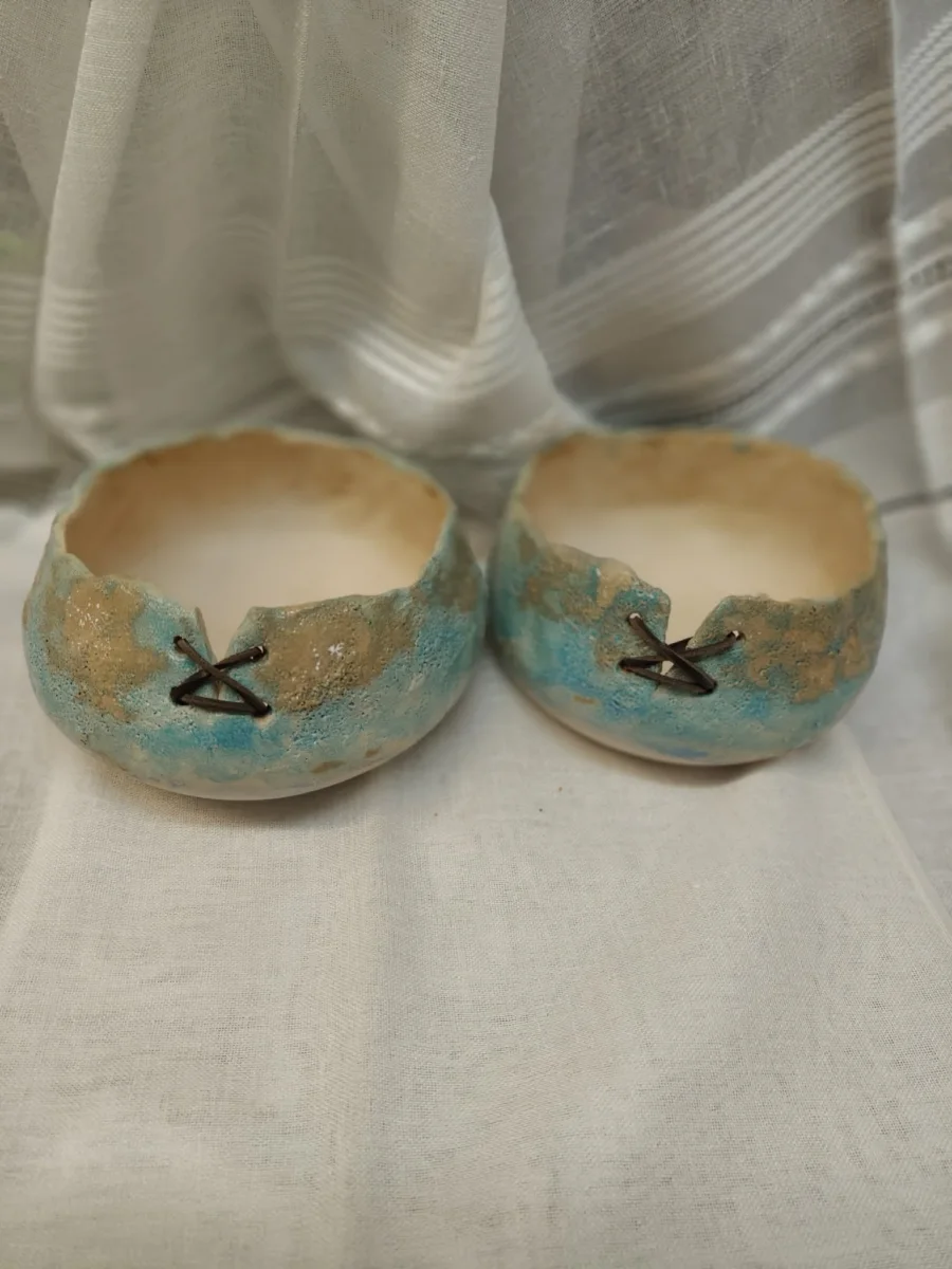 Dwie ceramiczne miseczki w odcieniach turkusu i piasku, z ciemnymi wiązaniami.